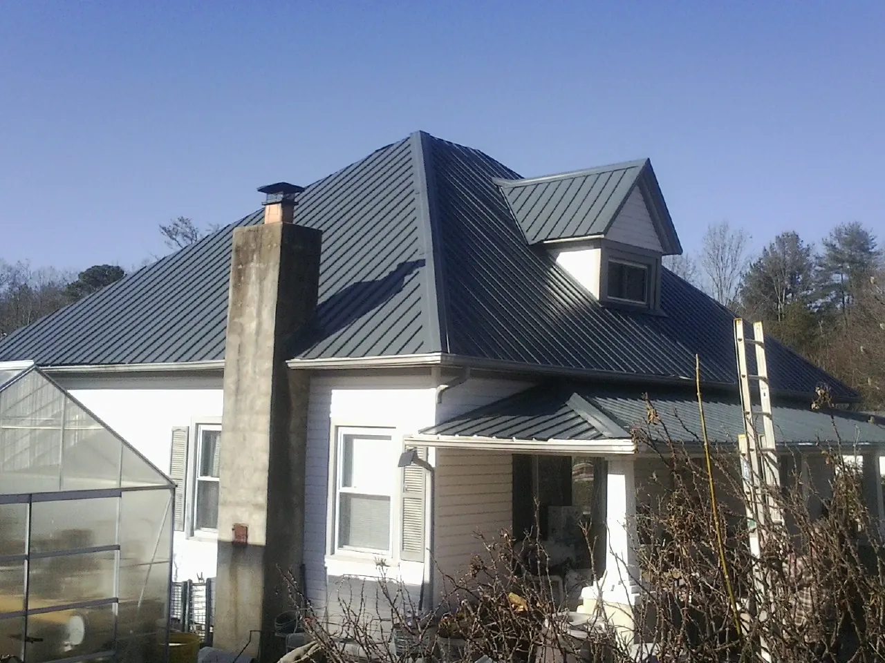 Dark blue standing seam metal roof on a white farmhouse with dormer — Slate & Tile Roof Repair by Roofing Brothers in Lake Bluff