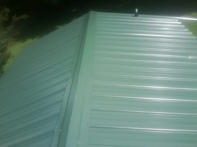New green metal panels meeting at the ridge of a roof — Flat Roof Repair work by our crew in Lake Bluff