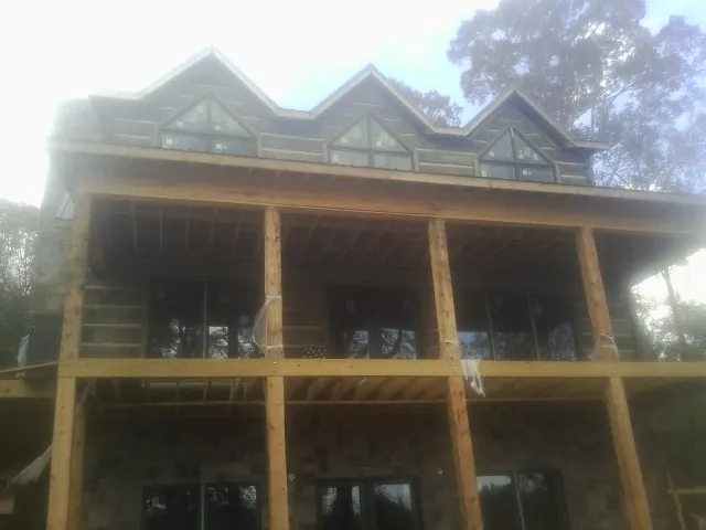 Dormers and porch framing on a large log home under construction — Roof Coating work by our crew in Lake Bluff