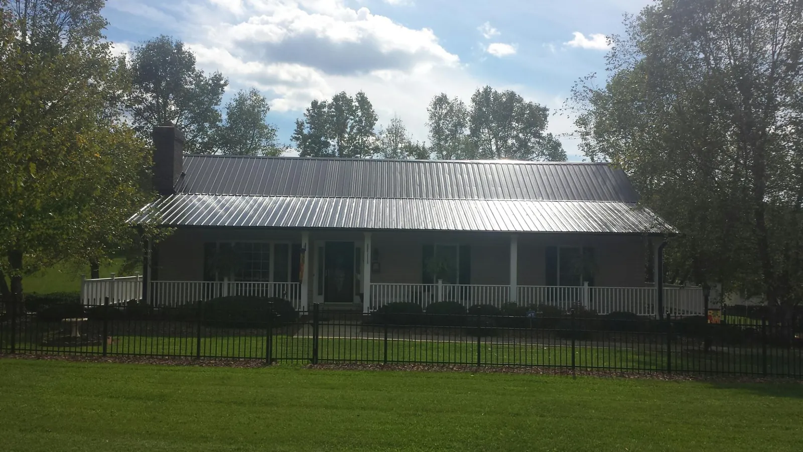 Gray metal roof on a brick ranch with a full width front porch — Gutter Guard Installation work by our crew in Lake Bluff