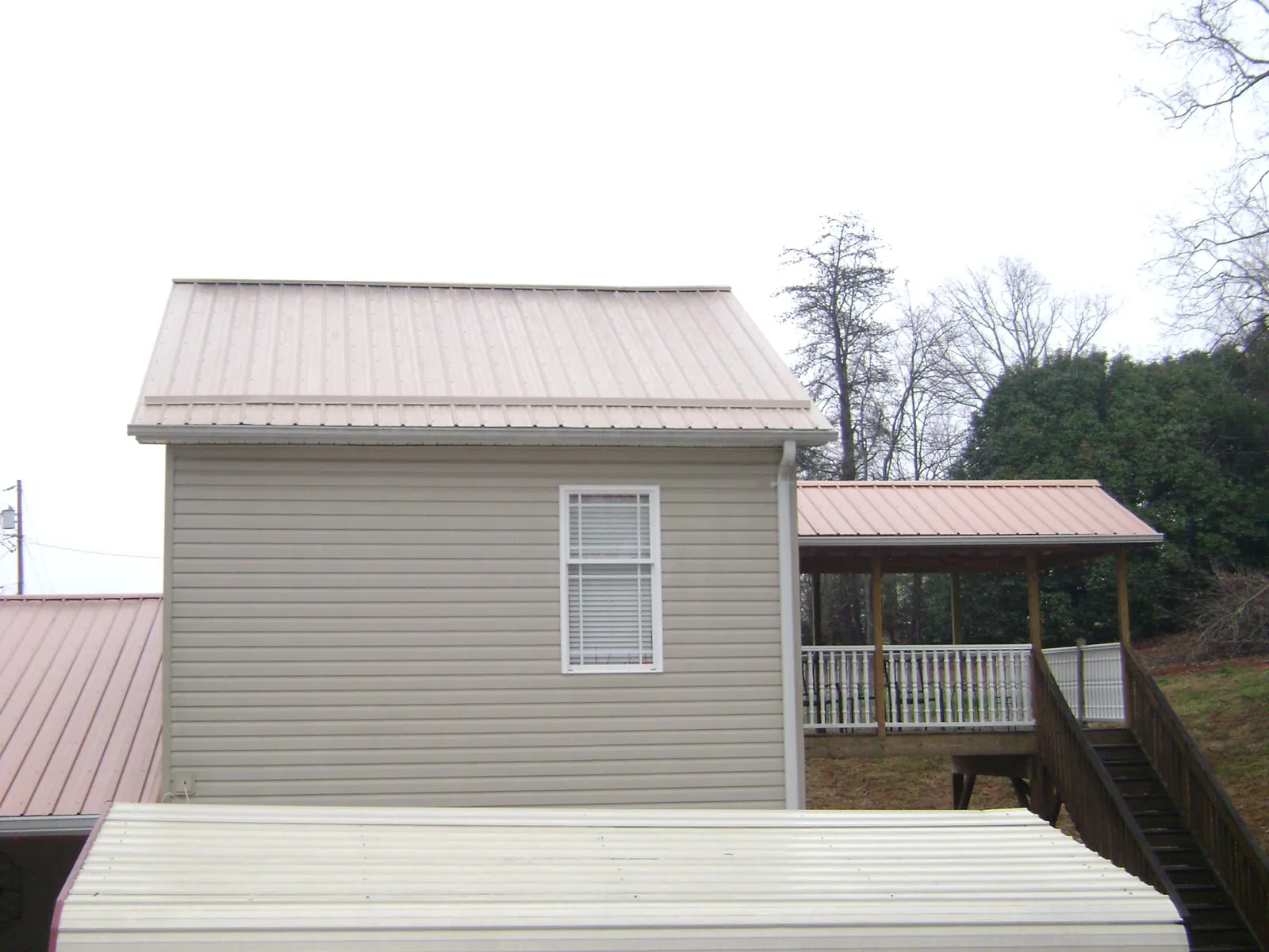 Tan metal roofs on a two story addition and attached porch, from a Roof Replacement job in Lake Bluff