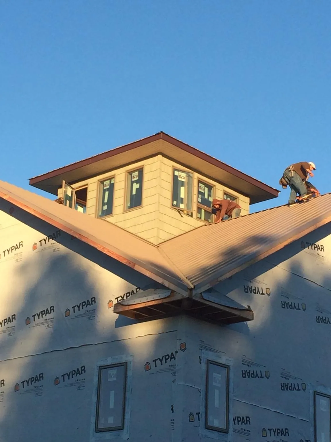 Roofers working around a rooftop cupola on a new metal roof at sunset — Roof Waterproofing in Lake Bluff by Roofing Brothers